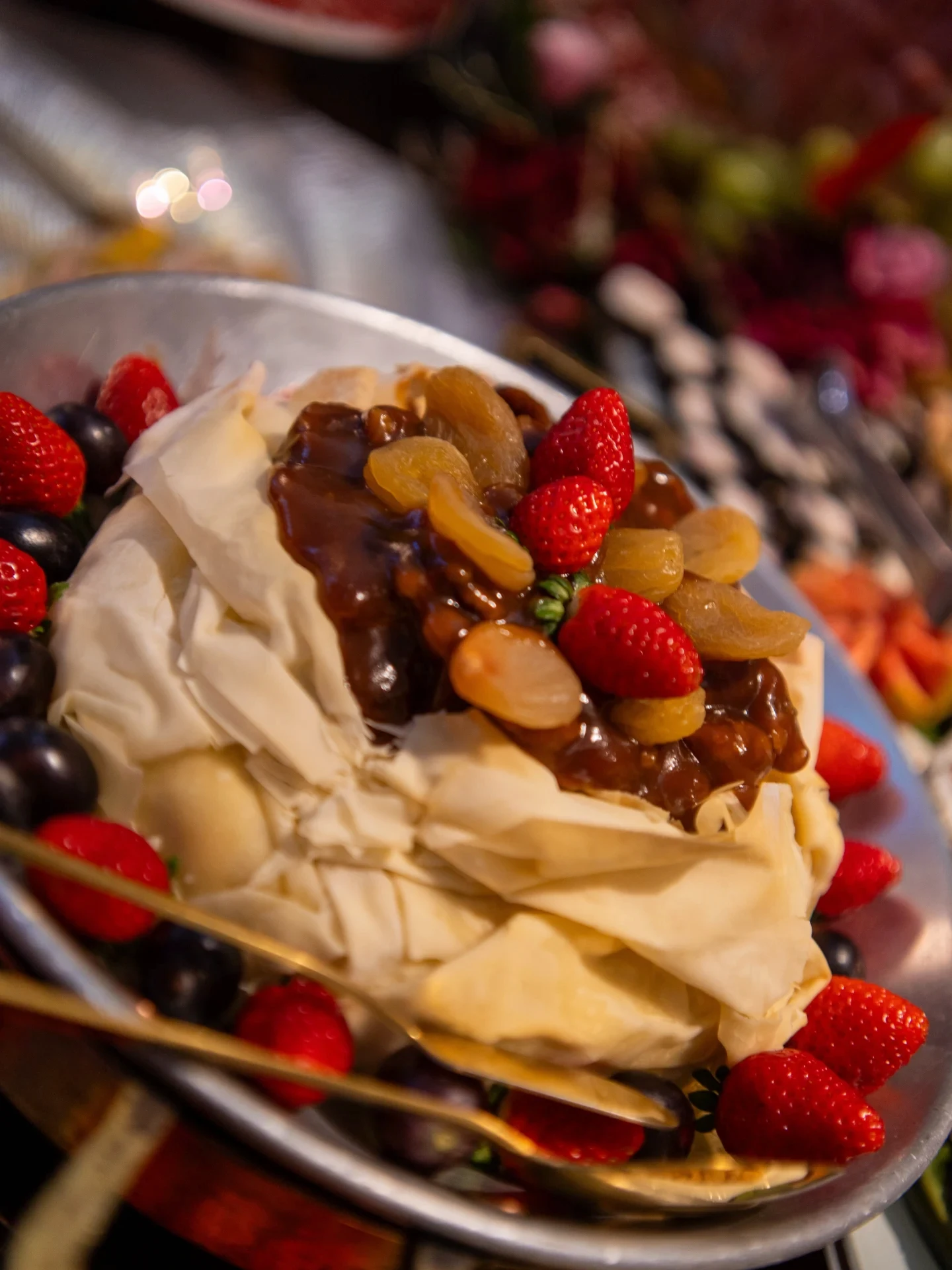 Sobremesa com morangos, uvas e merengue na mesa de doces.
