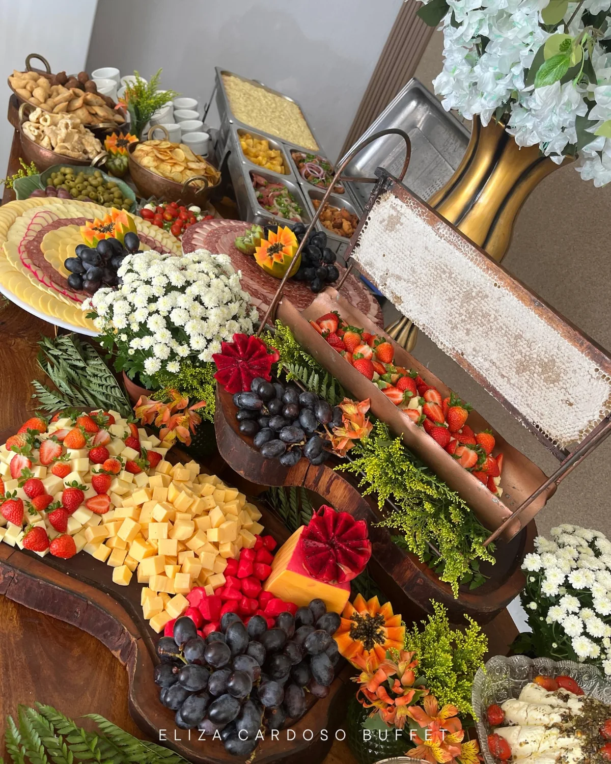 Mesa farta com frios, pães e frutas servida aos convidados.