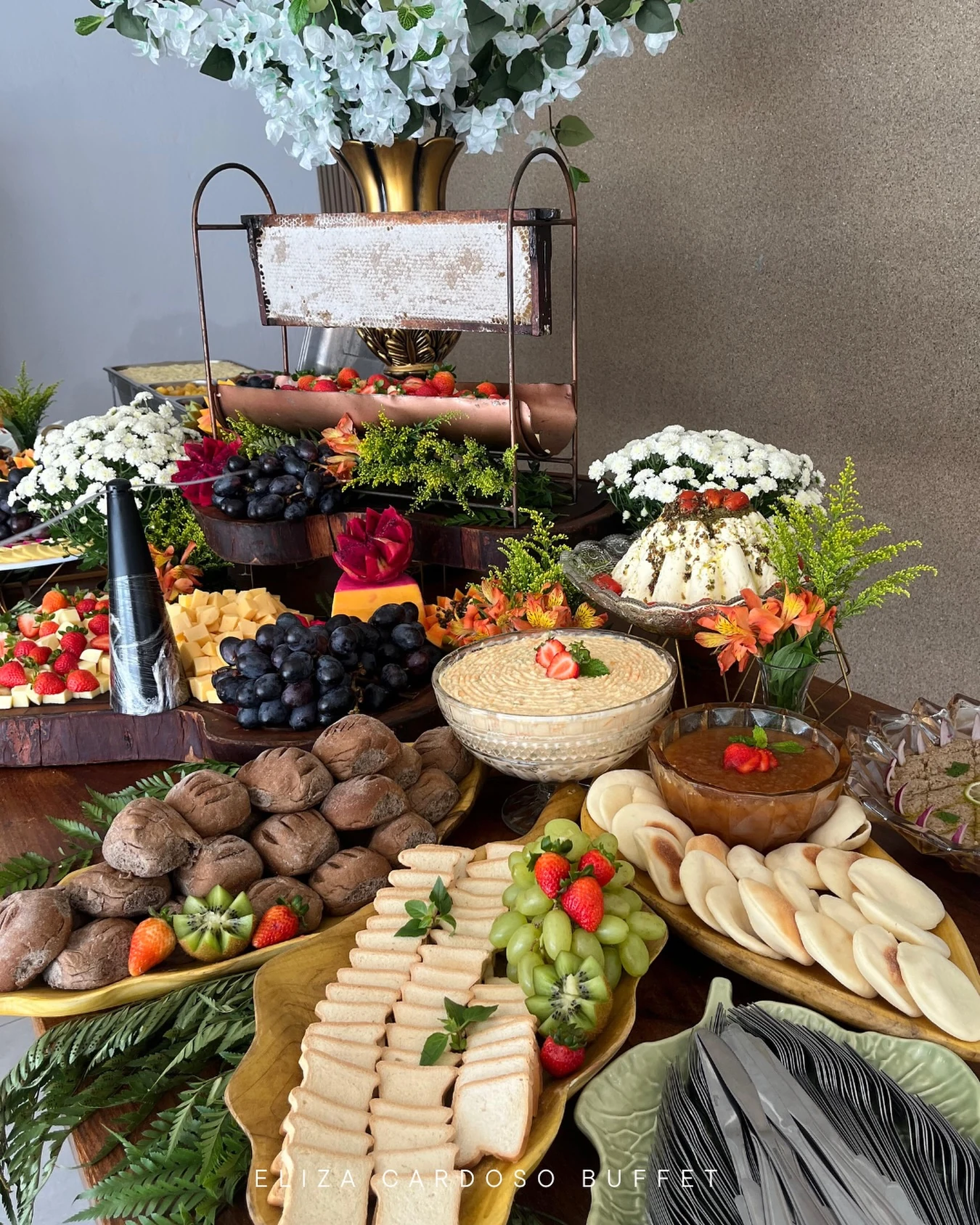 Tábua de queijos, pães e frutas servida no coffee break.